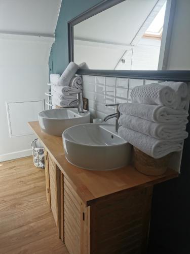 La salle de bains est pourvue de 2 lavabos, d'un miroir et de serviettes. dans l'établissement La P'tite Maison, à Bricqueville-sur-Mer