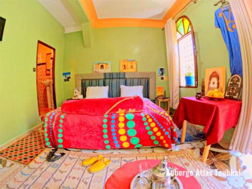 a bedroom with a bed covered in colorful sheets at Auberge Atlas Toubkal in Imlil
