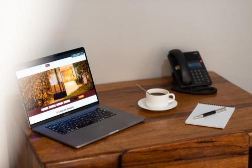 a laptop computer sitting on a desk with a cup of coffee at Le Lodge des Almadies in Dakar