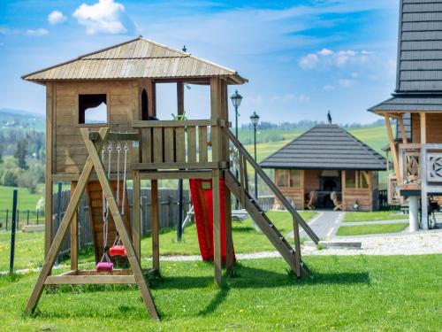 a wooden playground with a slide and a house at Osada Szaflary in Szaflary
