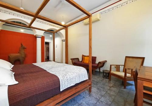 a bedroom with a bed and a desk and a chair at Saratha Vilas Chettinad in Kānādukāttān