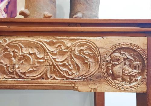 a wooden frame with a carving on a wall at Saratha Vilas Chettinad in Kānādukāttān