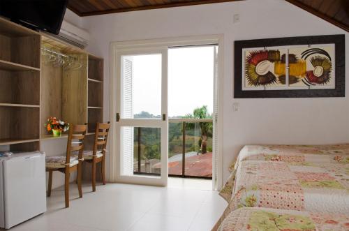 a bedroom with a bed and a table and a window at Pousada Florenza in Bento Gonçalves