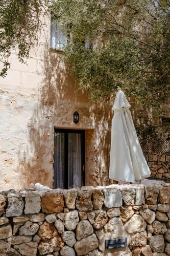 a white umbrella sitting next to a stone wall at Finca Gomera - Agroturismo Hotel in Cala Pi