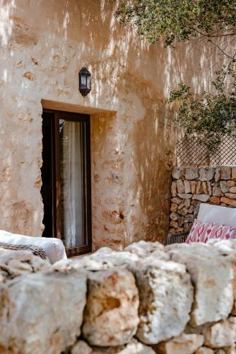 a building with a window and a stone wall at Finca Gomera - Agroturismo Hotel in Cala Pi