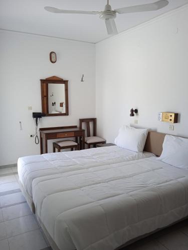 a large white bed in a room with a desk at Pal Beach in Palaiochóra
