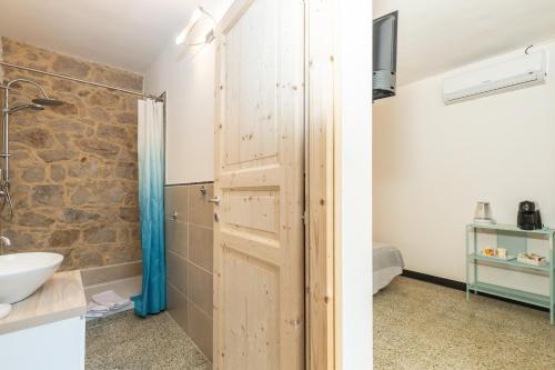 uma casa de banho com uma porta de madeira e um lavatório em LA TORRE DEI COLOMBO em Baunei