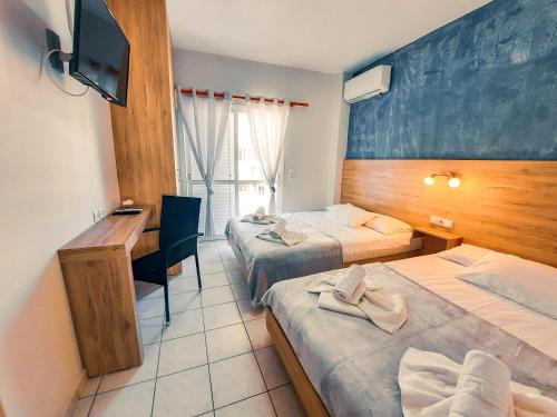 a hotel room with two beds and a desk at Rooms Anastasia Paralia in Katerini
