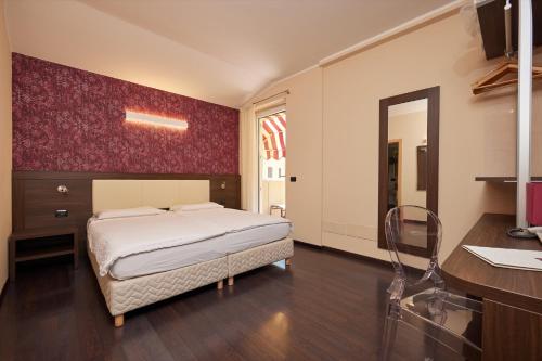a bedroom with a bed and a desk and a mirror at Hotel Villa Smeralda in Malcesine
