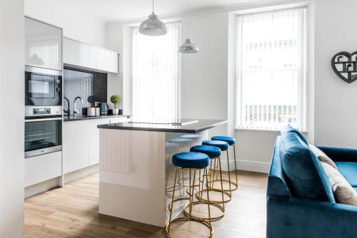 eine Küche mit weißen Schränken und blauen Stühlen in der Unterkunft Osprey Residence - Smart & Stylish Apartment in the Heart of Kendal in Kendal