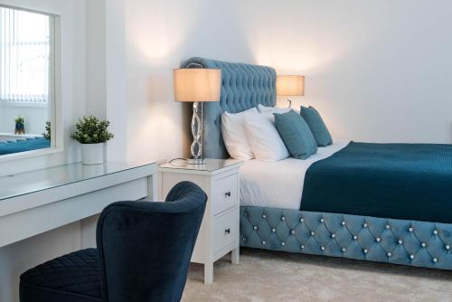 een slaapkamer met een bed en een bureau met een stoel bij Osprey Residence - Smart & Stylish Apartment in the Heart of Kendal in Kendal
