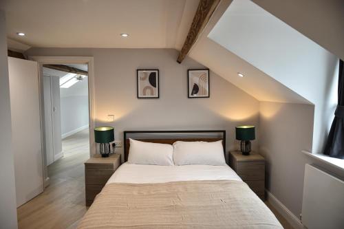 a bedroom with a bed and two lamps on night stands at Victoria Colonnade Aparthotel in Leamington Spa