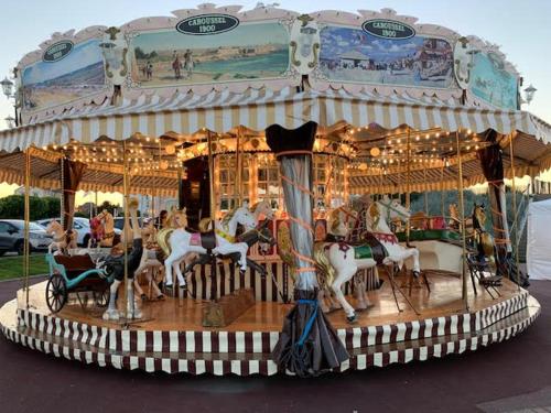 Un carrousel avec des gens à cheval sur lui dans l'établissement Jolie maison proche des commerces et de la plage, à Ouistreham