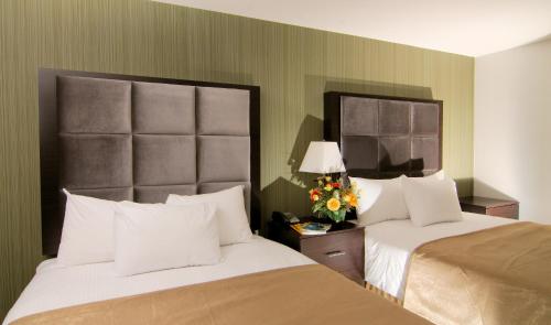 ein Hotelzimmer mit 2 Betten und Blumen auf dem Tisch in der Unterkunft Paradise Inn and Suites Redwater in Redwater