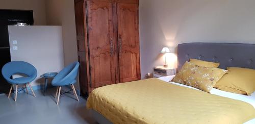 a bedroom with a bed and two blue chairs at L'Escampe in Saturargues