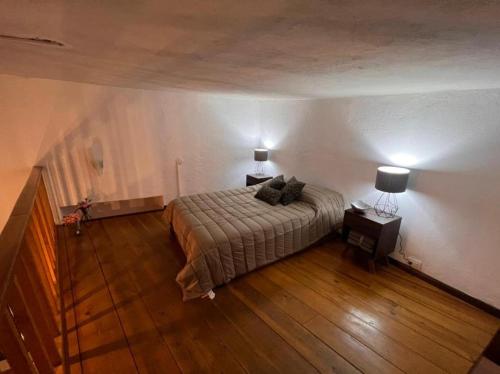 a bedroom with a bed and two lamps on a wooden floor at Casa Praxedis in Santiago