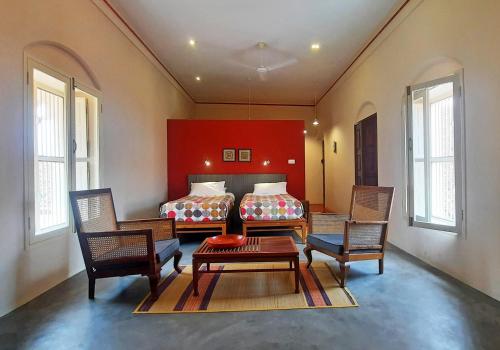 a bedroom with two beds and a table and chairs at Saratha Vilas Chettinad in Kānādukāttān