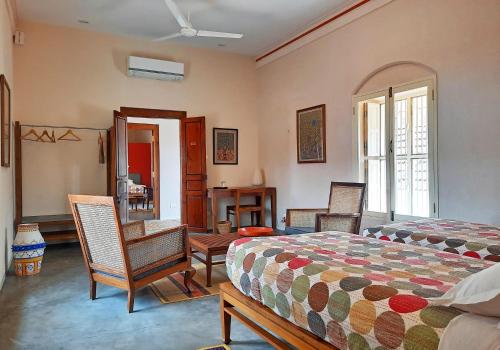 a bedroom with a bed and two chairs and a table at Saratha Vilas Chettinad in Kānādukāttān