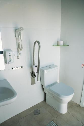 a white bathroom with a toilet and a sink at Hostal Brisas de Conil in Conil de la Frontera