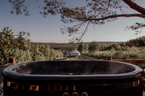 a large wooden tub sitting under a tree at Jurty z widokiem, prywatna balia- DZIKOLAS GLAMPING in Krasnobród
