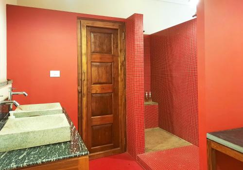 a bathroom with a sink and a shower with red walls at Saratha Vilas Chettinad in Kānādukāttān