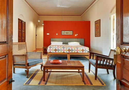 a bedroom with a bed and a table and chairs at Saratha Vilas Chettinad in Kānādukāttān