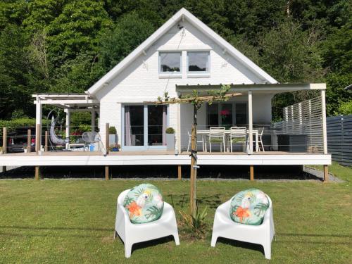 uma pequena casa branca com duas cadeiras no quintal em Villa Waulsort em Waulsort
