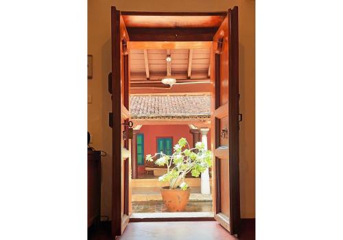 an open door into a hallway with a plant at Saratha Vilas Chettinad in Kānādukāttān