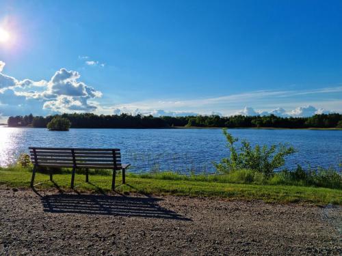 a park bench sitting on the shore of a lake at Bolmen Bed - Vandrarhem in Ljungby