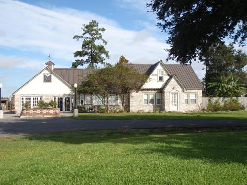 Eunice的住宿－L'Acadie Inn & RV Park，一座带草地庭院的大型白色房屋