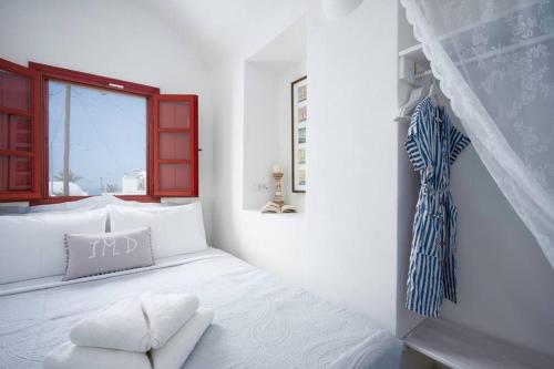 a white bedroom with a bed and a window at Casa Terra Vedema Oia - Privacy - Plunge Pool & Panoramic Sunset Terrace in Oia