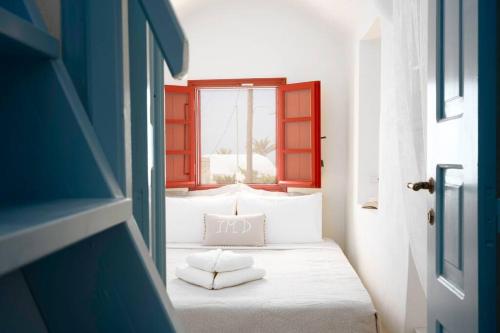 a bedroom with a white bed with a window at Casa Terra Vedema Oia - Privacy - Plunge Pool & Panoramic Sunset Terrace in Oia