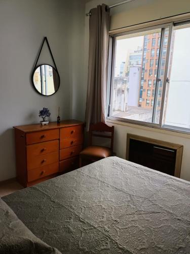 a bedroom with a bed and a dresser and a window at Apart hotel Centro Porto Alegre in Porto Alegre