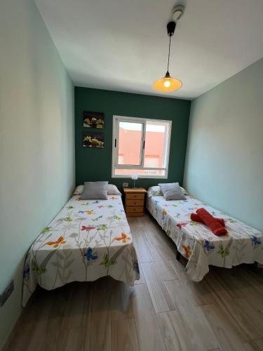 two beds in a room with green walls at Hostal-Private Room Descanso y Relax in Puerto del Rosario