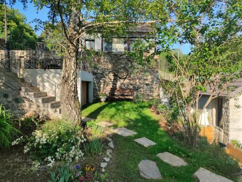 um jardim com uma árvore e um edifício de pedra em Le Secret du Moulin, agréable tiny house Villefort em Villefort