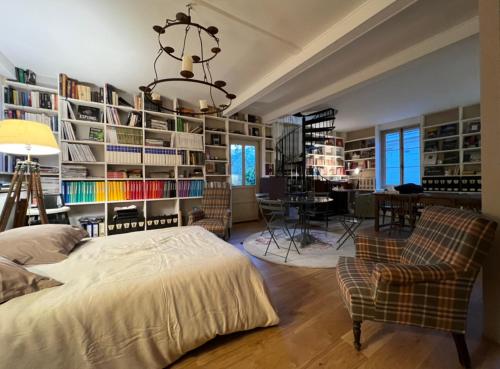 a bedroom with a bed and chairs and bookshelves at L'Atelier du Paysagiste - maison d'artiste in Giverny