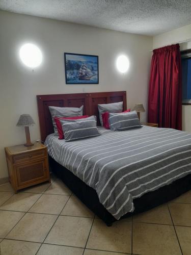 a large bed in a bedroom with a red curtain at Stella Maris 194 Amazimtoti Self Catering accommodation in Amanzimtoti