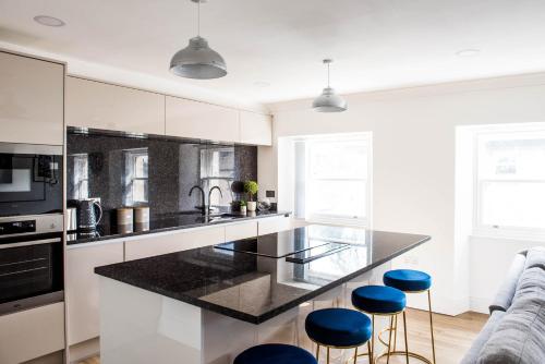 una cucina con piano di lavoro nero e sgabelli blu di Monterey Residence - Stunning, Duplex Apartment in the Heart of Kendal a Kendal