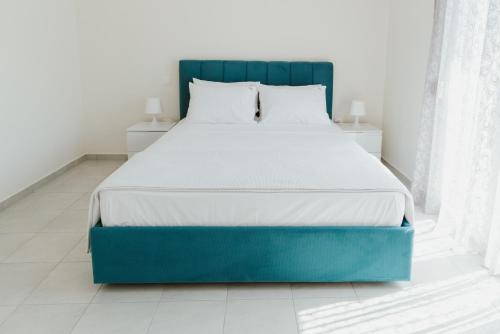 a bed with a blue headboard in a bedroom at BLUE AND WHITE LUXURY suites in Nea Kalikratia