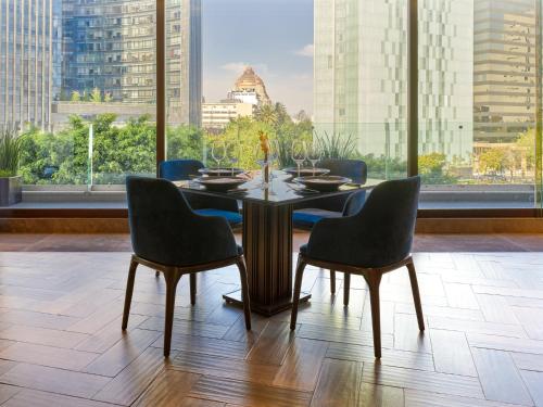 a dining room with a table and chairs and a large window at Fiesta Americana Reforma in Mexico City