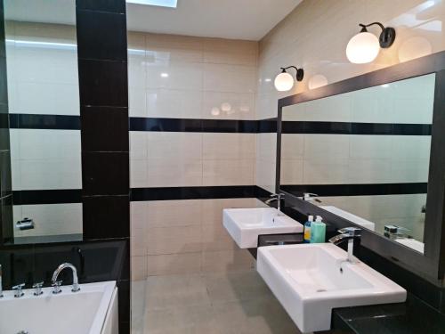 a bathroom with two sinks and two mirrors at Pearl Residences Sleep 27 in Batu Ferringhi