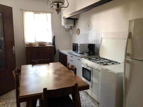 La cuisine est équipée d'une table, d'une cuisinière et d'un réfrigérateur. dans l'établissement Maison vue mer et montagne, à Cervione