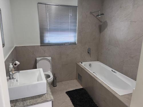 a bathroom with a tub and a sink and a toilet at Mafini Villa in Centurion