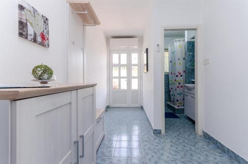 cocina con armarios blancos y ducha a ras de suelo en Apartments Marotin, en Rab