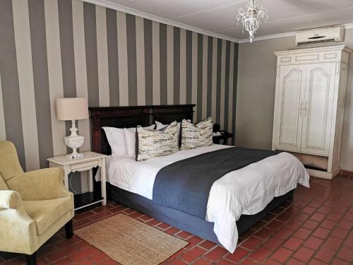 um quarto com uma cama grande e uma cadeira em Pecan Manor em Hartbeespoort