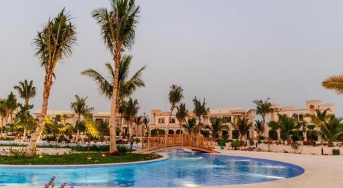 un complexe avec une grande piscine bordée de palmiers dans l'établissement HAWANA RESORT VILLA, à Salalah