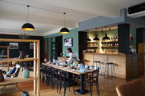 a person standing at a table in a restaurant at Hotel Stancia Kazbegi - City Center in Stepantsminda