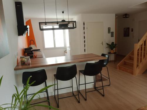 uma cozinha com um balcão de madeira e bancos pretos em Villa perpignanaise em Perpignan