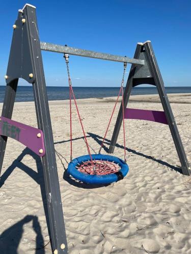 a swing on the beach with the ocean in the background at Piejūras māja skandināvu stilā! Seaside scandi house! in Lapmežciems