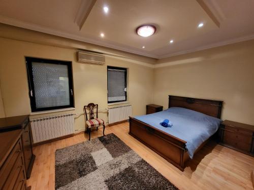 a bedroom with a bed and a desk and two windows at EDEN Residence in Skopje